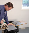 installing a waterproof vapor barrier on a basement floor to prepare for basement carpeting in a Cicero home