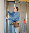 Insulated basement wall panels being placed against a concrete foundation wall in Cortland